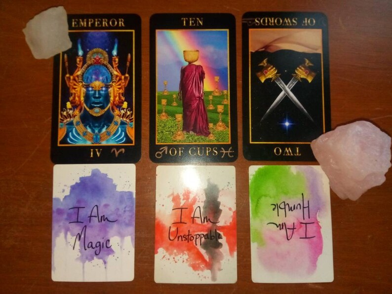 以下が含まれることがあります： タロットカードリーディングで、皇帝、カップの10、ソードの2、そして「私は魔法だ」「私は止められない」と書かれた2枚のアファメーションカードを含む5枚のカードを使用しています。
