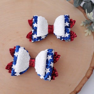 May include: Two red, white, and blue glitter hair bows with a star pattern.