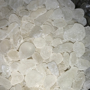 May include: A close-up view of a bowl filled with small, white, translucent, irregularly shaped glass stones.
