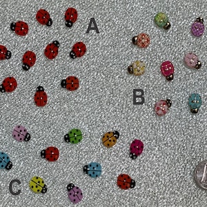 May include: Assortment of colourful ladybug-shaped buttons with various patterns and designs. The buttons are arranged in three groups labelled A, B, and C.