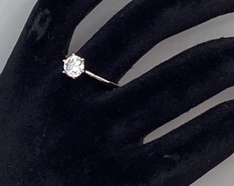 May include: A silver ring with a large, clear, round gemstone.