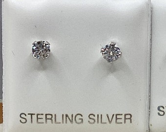 May include: Two pairs of sterling silver stud earrings with clear, sparkling cubic zirconia stones. Each earring is displayed on a white card with the words "STERLING SILVER" printed in black.