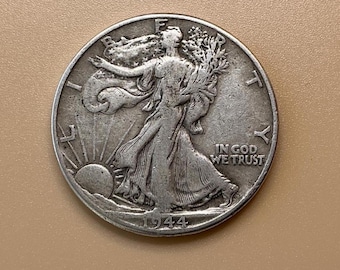 Op de afbeelding: Een zilveren Walking Liberty half dollar munt uit 1944. De munt toont Lady Liberty die naar de zon loopt en takken vasthoudt. De woorden "IN GOD WE TRUST" zijn zichtbaar. De munt is rond en heeft een versleten uiterlijk.