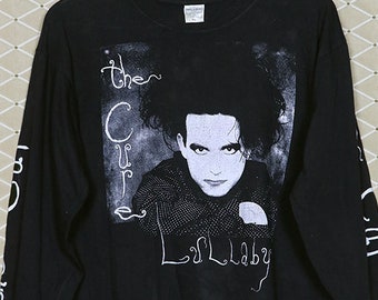 May include: Black long-sleeve t-shirt with a white print of Robert Smith, the lead singer of The Cure, and the text "The Cure" and "Disintegration".