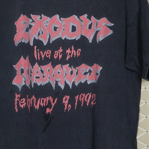 May include: Black t-shirt with a pink graphic of the band Exodus. The graphic says "Exodus live at the Marquee February 9, 1992".