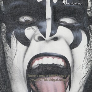 May include: A black and white illustration of a person with a demon-like face, with a large open mouth and tongue sticking out. The text "There's now a SHIRT shop at www.CTMadrigal.com" is visible at the bottom of the image. The text "Madrigalgallery" is visible in the top right corner of the image.