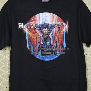 Puede incluir: Camiseta negra con un estampado gr&aacute;fico de Lobezno corriendo por un callej&oacute;n de la ciudad. El gr&aacute;fico est&aacute; en un c&iacute;rculo con el texto "There's now a shop at www.TMadrigal.com".