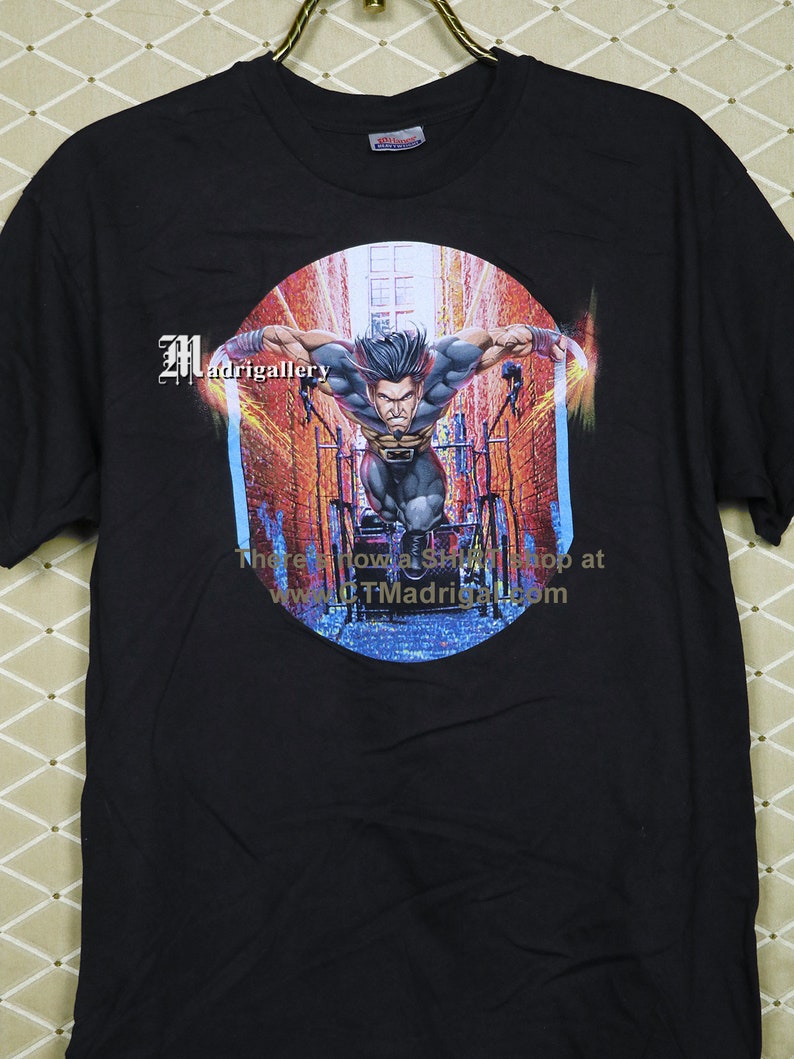 Puede incluir: Camiseta negra con un estampado gr&aacute;fico de Lobezno corriendo por un callej&oacute;n de la ciudad. El gr&aacute;fico est&aacute; en un c&iacute;rculo con el texto "There's now a shop at www.TMadrigal.com".