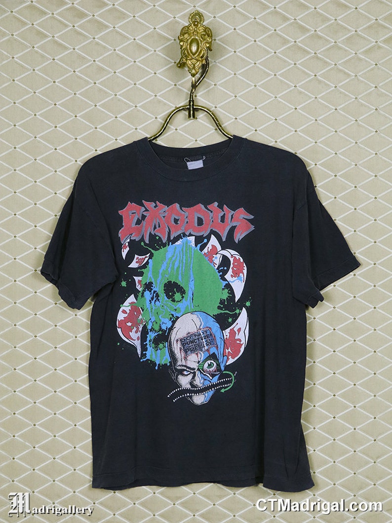 May include: Black t-shirt with a graphic print of a skull with a green and blue face and the word "Exodus" in white letters.