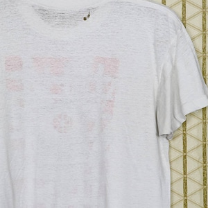 May include: White t-shirt with a faded pink graphic on the back. The graphic is a logo with the text "F.U.N."