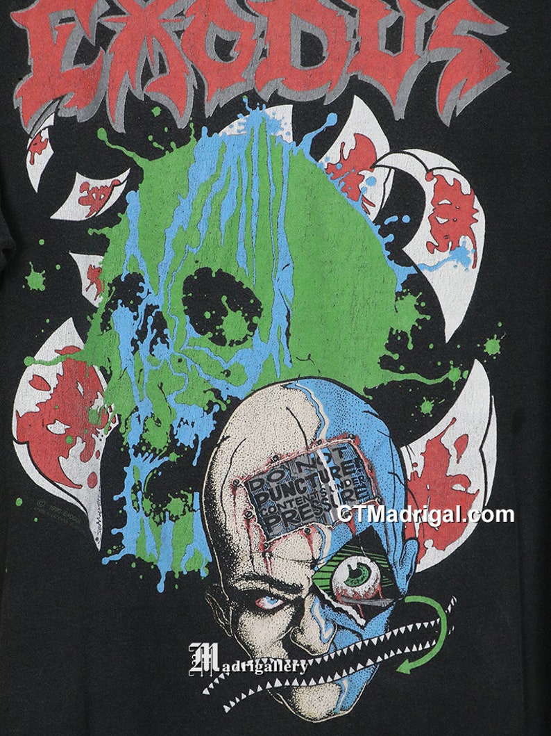 May include: Black t-shirt with a green, blue, and red graphic of a skull with the text "DO NOT PUNCTURE CONTENTS UNDER PRESSURE" on the forehead. The band name "EXODUS" is printed in red at the top of the shirt.