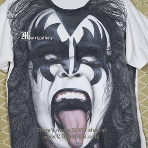 May include: White t-shirt featuring a black and white image of a person with long black hair and a face painted with black and white makeup. The person is wearing a black and white costume. The text "There's now a SHIRT shop at www.CTMadrigal.com" is printed on the bottom of the shirt.