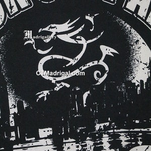 May include: Black and white graphic t-shirt with a distressed design. The shirt features a dragon with the text "Madrigal" and "CTMadrigal.com".