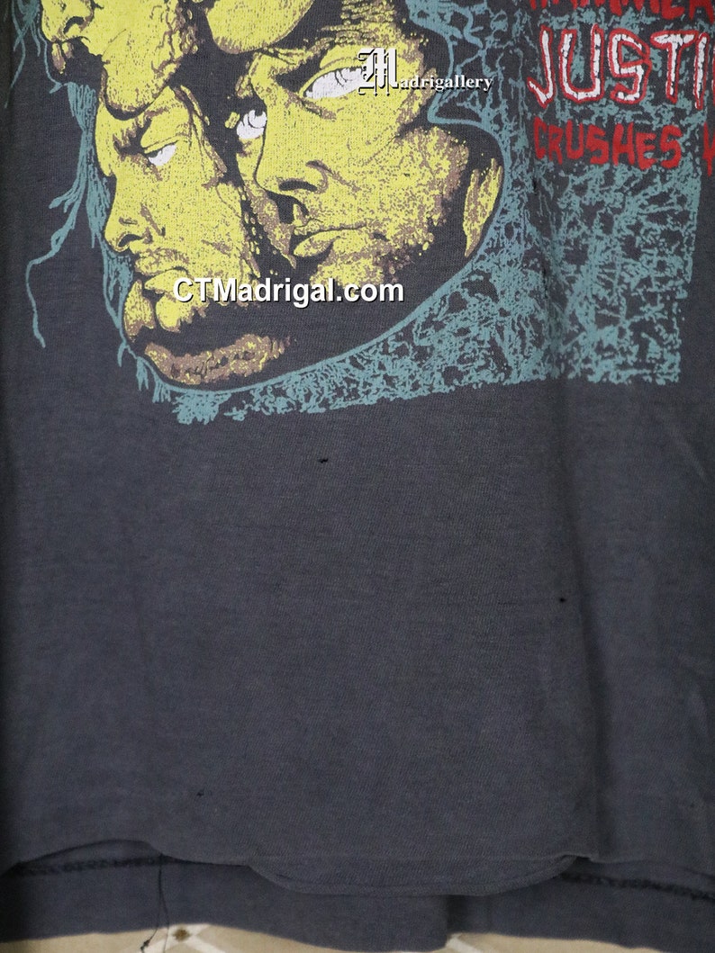May include: A dark gray t-shirt with a faded graphic print of three faces and the text "JUSTICE CRUSHES" in red and white.