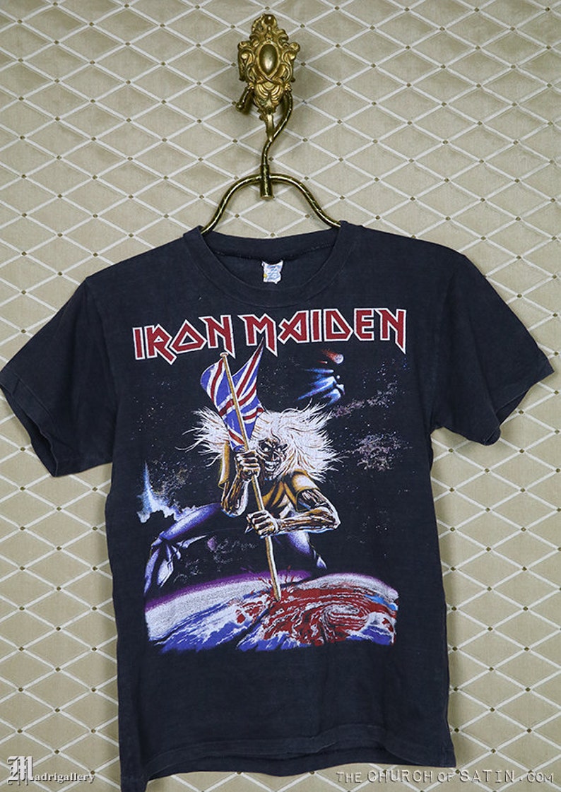 May include: Black t-shirt with a graphic print of a figure holding a flag with the text "IRON MAIDEN" above it.