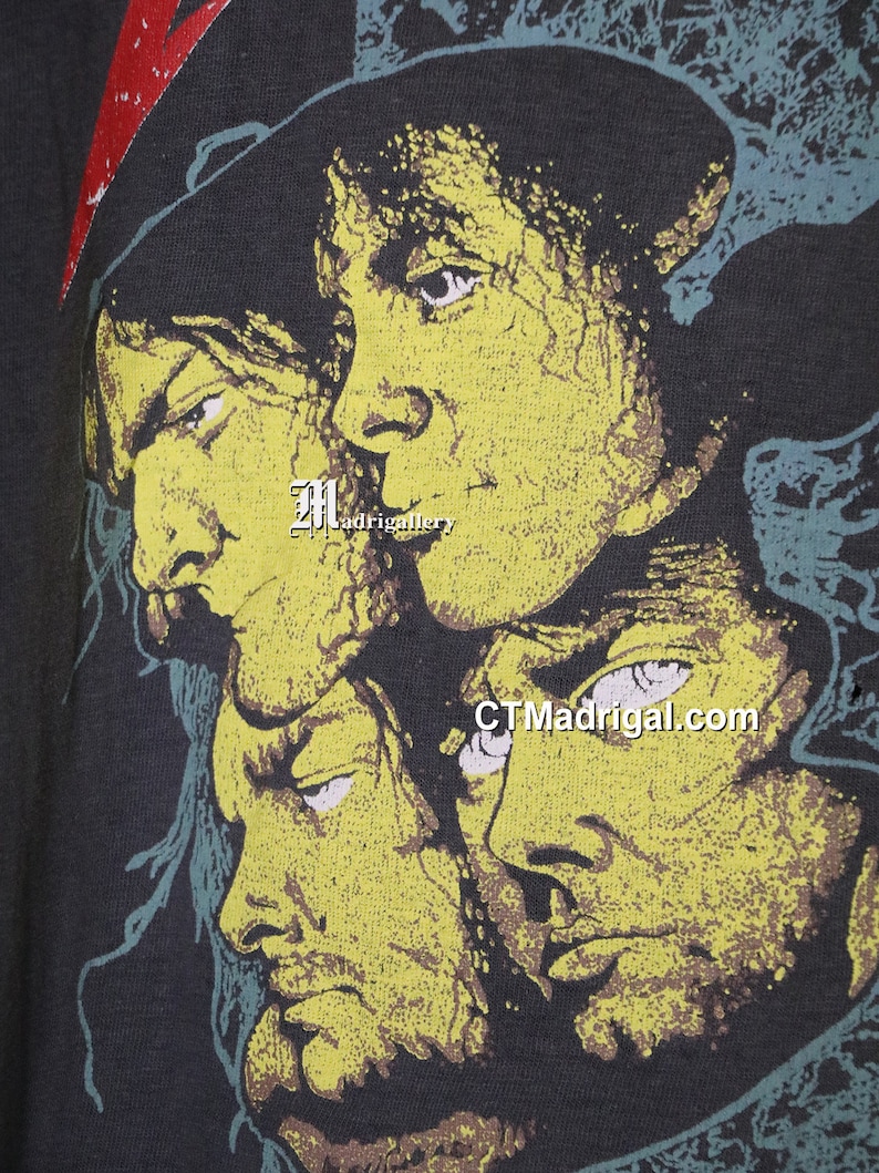 May include: A black t-shirt with a yellow and green print of four faces. The faces are of men with long hair and beards. The text "CTMadrigal.com" is printed on the shirt.