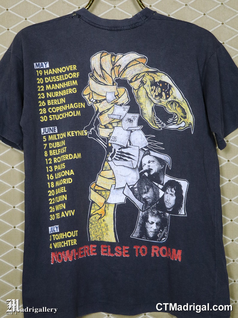 K&ouml;nnte beinhalten: Schwarzes T-Shirt mit einem Grafikdruck eines Skeletts mit einem bandagierten Kopf. Die Grafik ist von einem gelben Band mit Daten und Orten f&uuml;r eine Tour umgeben. Der Text "NOWHERE ELSE TO ROAM" ist unterhalb der Grafik gedruckt.