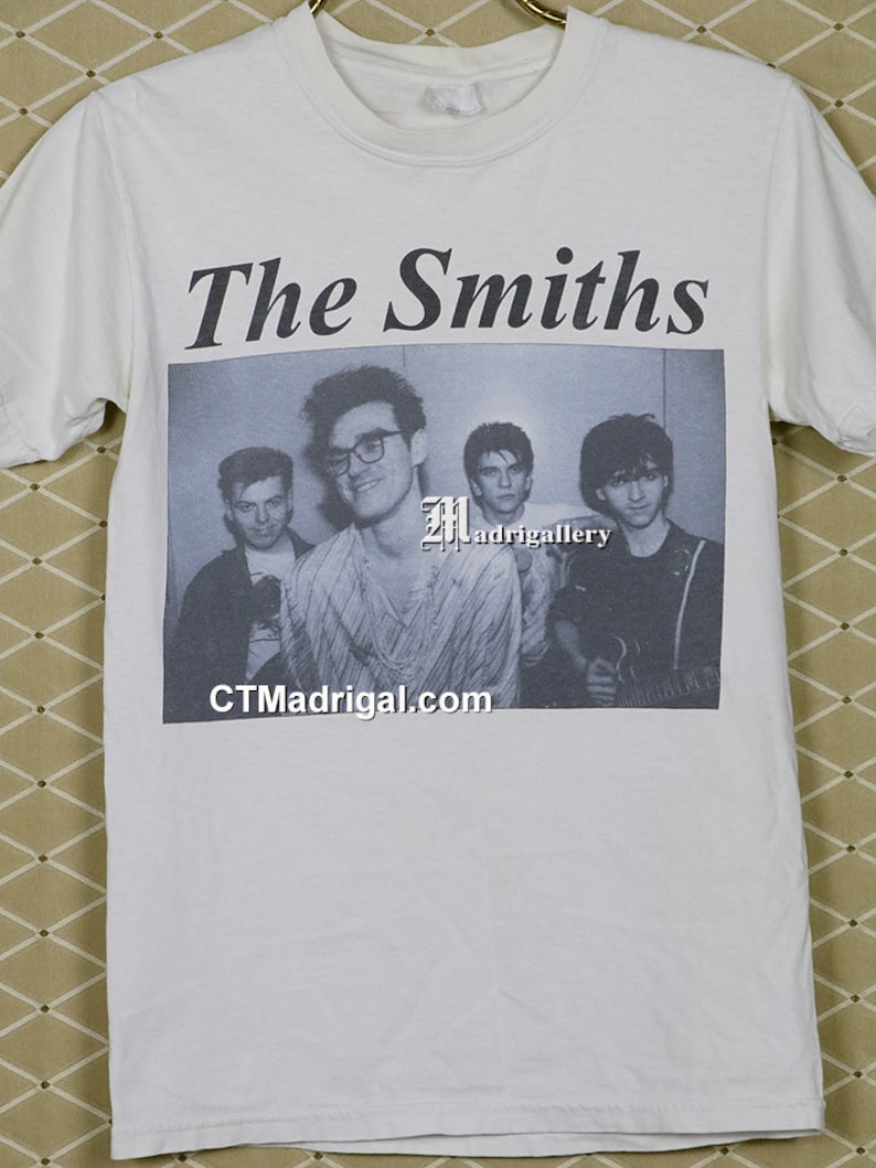 K&ouml;nnte beinhalten: Wei&szlig;es T-Shirt mit einem Schwarz-Wei&szlig;-Bild der Band The Smiths. Der Name der Band ist in fetter, schwarzer Schrift &uuml;ber dem Bild gedruckt. Die Website CTMadgrigal.com ist darunter abgebildet.