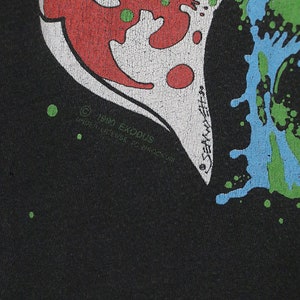 May include: Black t-shirt with a red, white, and green graphic print of a heart with a skull inside. The text "1989 Exodus" is printed on the bottom of the heart.