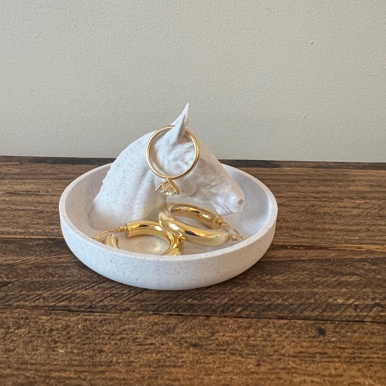 May include: White ceramic horse head ring holder with a small white ceramic dish. The dish contains three gold hoop earrings.