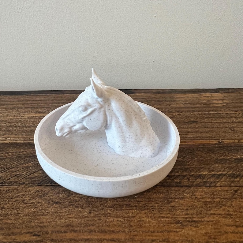 May include: White ceramic trinket dish with a horse head sculpture on the side. The dish has a speckled finish.