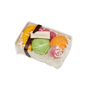 Op de afbeelding: Een transparante plastic cadeaumand gevuld met chocolade fruitvormige snoepjes. De mand is gevuld met gescheurd papier en bevat een gele banaan, een groene appel, een sinaasappel, een roze aardbei en een rode framboos. De mand heeft een bruin lint en een label met de tekst "chocochoc" met de tagline "Lovely Handmade in London, England".