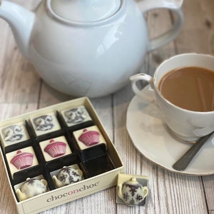 May include: A box of assorted chocolate truffles with a teapot, cupcake, and other tea-themed designs. The box is labelled "chocochoc".