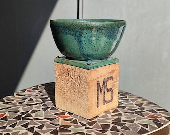 Handmade ceramic bowl in green on a wooden base