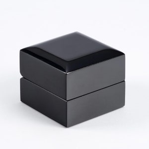 May include: A black square ring box with a glossy finish.