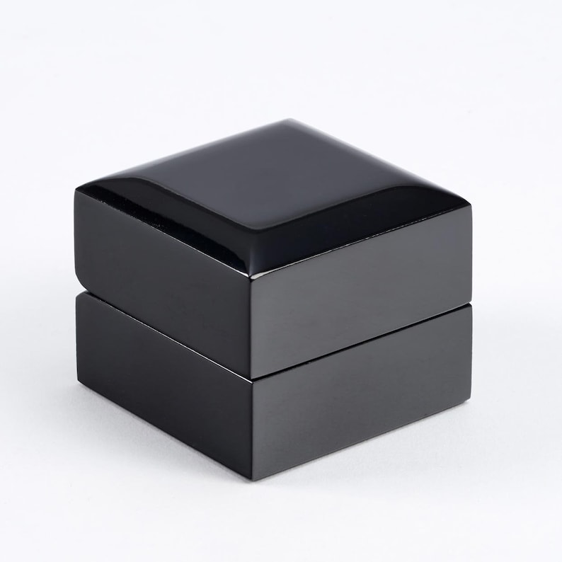 May include: A black square ring box with a glossy finish.