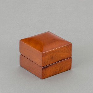 May include: A wooden box with a hinged lid. The box is a rich brown color and has a smooth, polished finish.