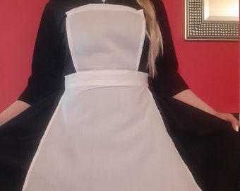May include: A black and white maid's uniform with a white apron and a white collar. The apron has a rounded bottom and a white belt.
