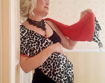 May include: A black and white dalmatian print shawl with a red trim is draped over a black top. A red shawl is held up, revealing a black and white polka dot pattern. A black lace choker necklace is worn.