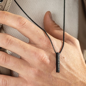 May include: A black chain necklace with a black bar pendant engraved with the text "DAVID & EMILY"