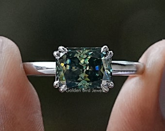 May include: A silver ring featuring a square-shaped green gemstone. The gemstone has a distinctive, multi-faceted cut that catches the light.