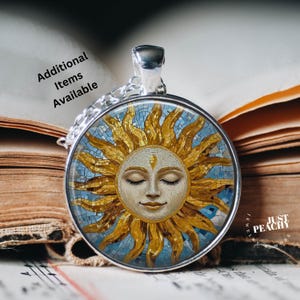 Może przedstawiać: Okazały naszyjnik z okrągłą zawieszką z mozaikowym wzorem słońca, przedstawiający uśmiechniętą twarz z zamkniętymi oczami. Słońce ma złote i niebieskie akcenty, a zawieszka wisi na srebrnym łańcuszku. Tekst "Additional Items Available" jest widoczny.