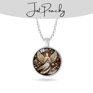 Op de afbeelding: Een zilverkleurige hangerketting met een ronde bedel met een engelontwerp in glas-in-loodstijl. De engel houdt een ster vast, omringd door gouden sterren, rode en witte bloemen en de tekst "Just Peachy".