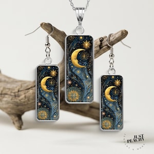 May include: A silver-toned jewelry set consisting of a rectangular pendant necklace and two matching rectangular drop earrings. Each piece features a dark blue celestial design with a golden crescent moon, stars, and a compass-like star motif.