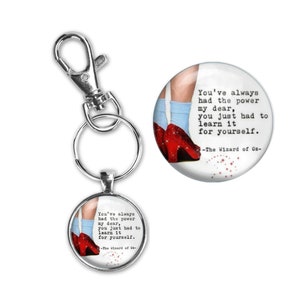 May include: A silver keychain with a round charm featuring a girl wearing red shoes and a quote from The Wizard of Oz: "You've always had the power my dear, you just had to learn it for yourself."