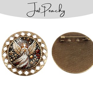 Op de afbeelding: Een ronde, bronskleurige broche met een engelontwerp. De engel houdt een ster vast, omringd door sterren en bloemmotieven. De broche heeft een decoratieve, opengewerkte rand en een speldrug. De tekst "Just Peachy" staat bovenaan.