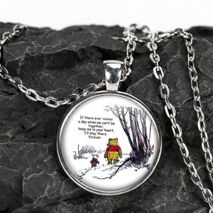 May include: A silver chain necklace with a round glass pendant featuring a black and white illustration of Winnie the Pooh and Piglet walking in a forest. The pendant has a white background and the text "If there ever comes a day when we can't be together, keep me in your heart, I'll stay there forever."