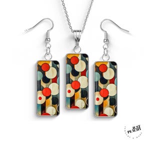 May include: A silver necklace and matching earrings set. The rectangular pendants feature a colorful abstract design of red, white, blue, and yellow circles. The jewelry set is displayed on a white background.