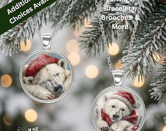 May include: Two silver-toned pendant necklaces featuring circular glass cabochons. Each pendant displays a detailed illustration of a white polar bear wearing a red knit hat. The necklaces have thin silver-toned chains and round metal frames.