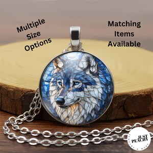 May include: A round silver-toned pendant necklace featuring a stained-glass style illustration of a wolf with blue and white fur. The text "Multiple Size Options" and "Matching Items Available" appears above, with a "JUST PEACHY" logo below.