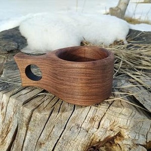 May include: A wooden drinking cup with a handle, made from dark walnut wood. The cup has a smooth, rounded interior and a natural wood finish.