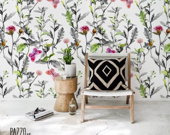 May include: A white background with a black and green floral pattern featuring butterflies and flowers. A wooden chair with a black and white geometric patterned cushion sits in front of the wall. A small wooden side table with a glass of water sits next to the chair. The text "PAZZO walls" is at the bottom of the image.