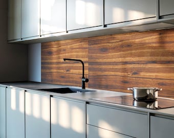 May include: A modern kitchen with gray cabinets and a wood-look backsplash. A black faucet is mounted above a stainless steel sink. A black electric stovetop is installed in the countertop. A silver pot is sitting on the stovetop.