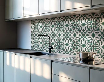 May include: A modern kitchen with white cabinets and a green and white patterned tile backsplash. A black faucet is mounted above a stainless steel sink. A black stovetop is visible in the foreground.
