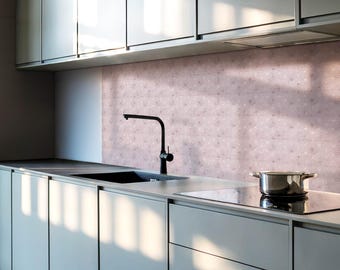 May include: A modern kitchen with gray cabinets and a stainless steel stovetop. The backsplash is a light pink with a subtle pattern. A black faucet is mounted above a black sink.