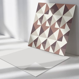 May include: A square tile featuring a geometric pattern of brown, beige, and white triangles. The tile is made of ceramic and has a glossy finish.